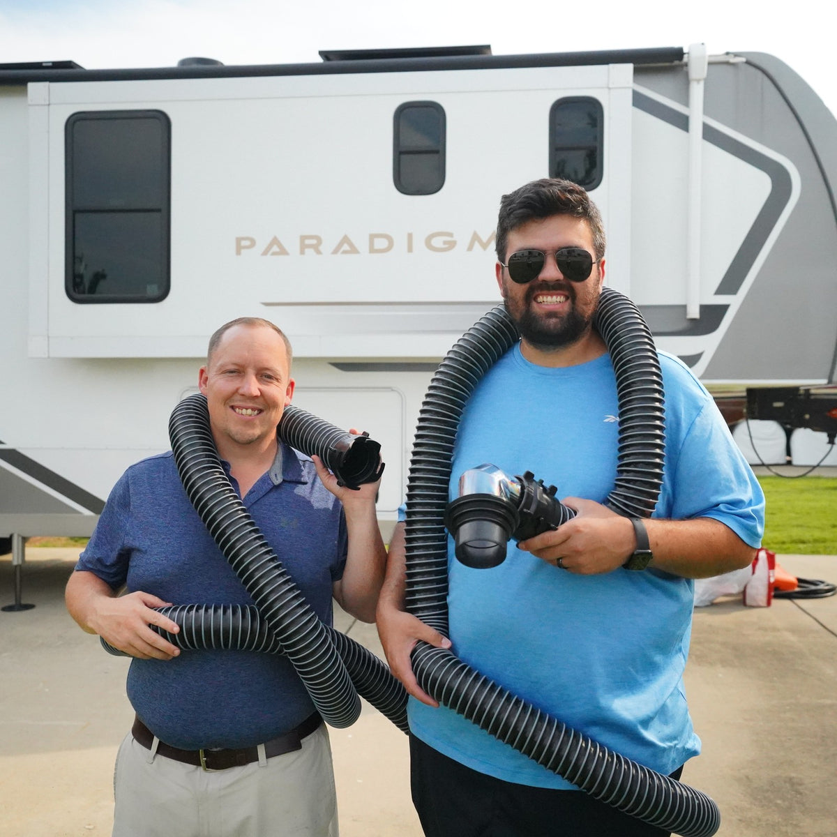Matt and Wil, founders of Gravity, holding the sewer hose kit in front of their RV